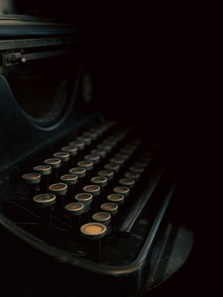 Close-up of an antique typewriter in dim lighting on a black background.