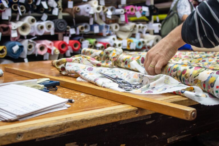 Close-up of hands cutting fabric in a tailor shop, showcasing craftsmanship.
