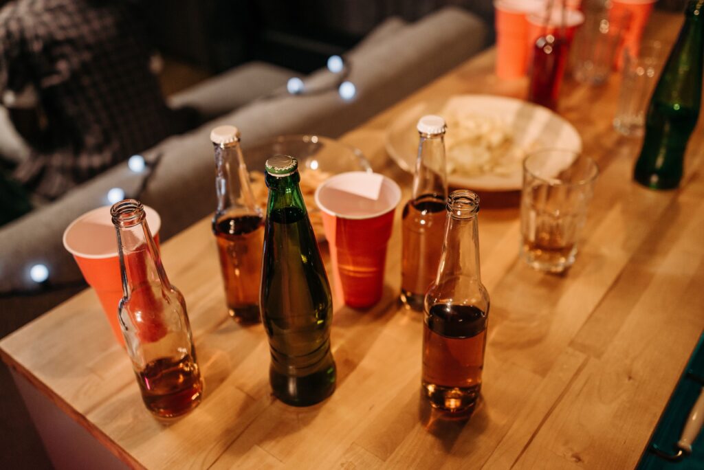 A vibrant party setup with beer bottles and cups on a wooden table indoors.